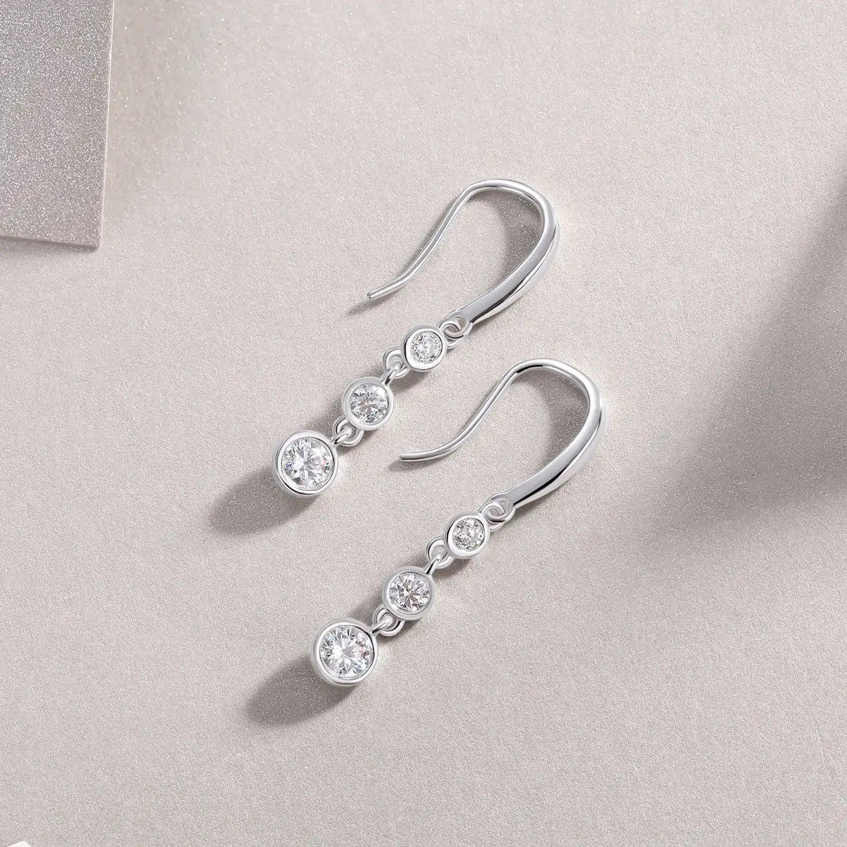 Silver earrings with clear stones on a light gray background
