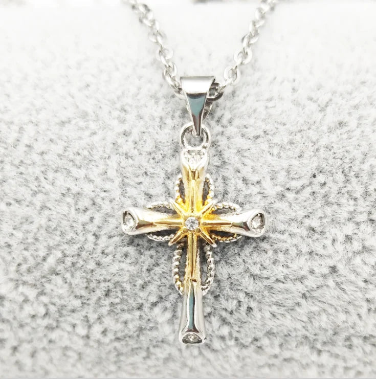 Gold and silver cross pendant on a chain against a gray background