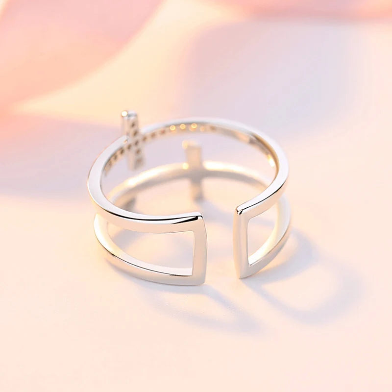 Silver open ring with geometric design on a soft pink background