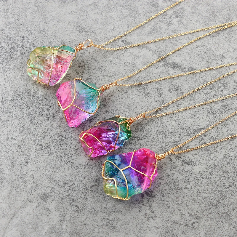 Colorful crystal pendants on gold chains against a gray stone background