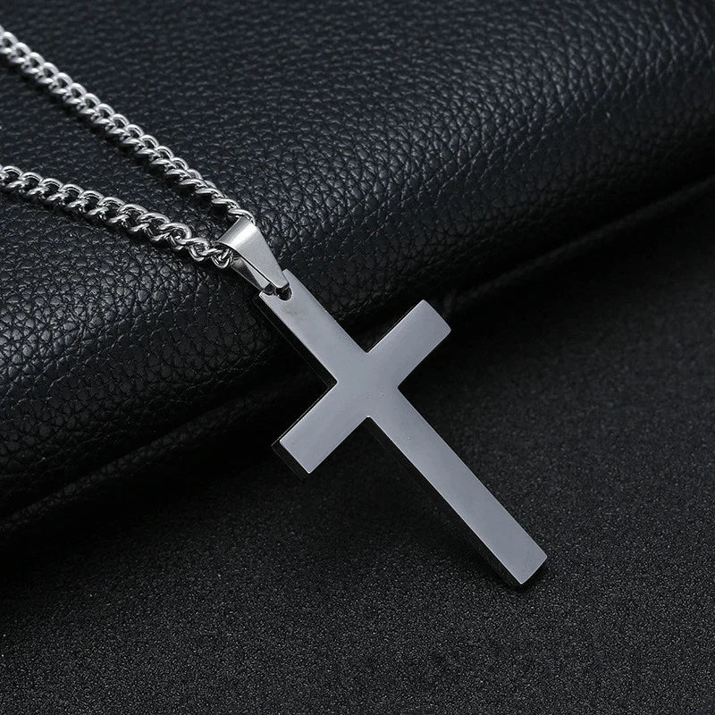 Silver cross pendant necklace on a black leather surface
