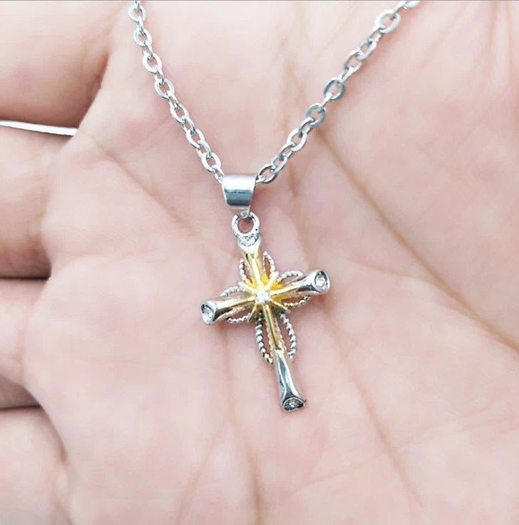 Silver necklace with a cross pendant on a hand