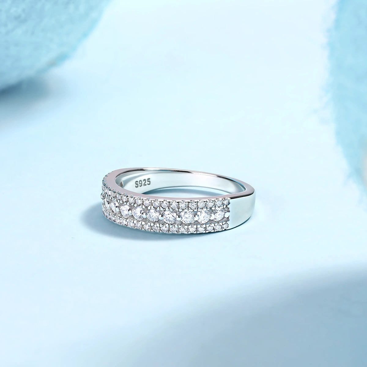 Sterling silver pave moissanite wedding band ring with blue background
